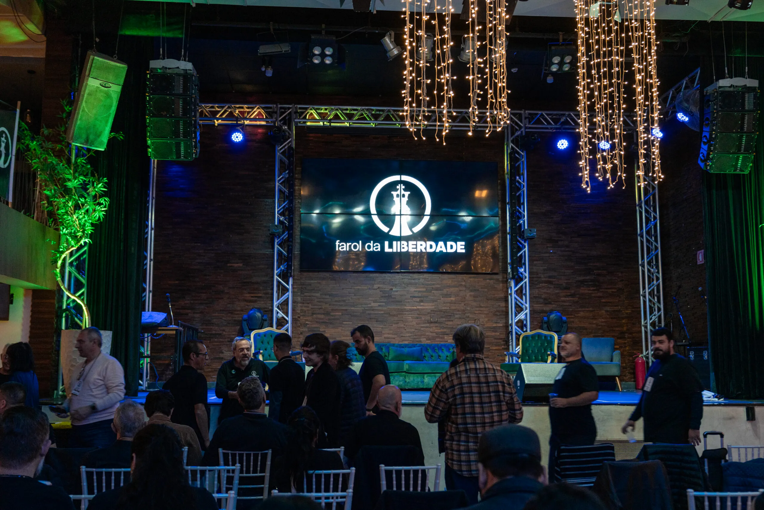 Público diante do palco do congresso, com o logo do Farol da Liberdade no telão